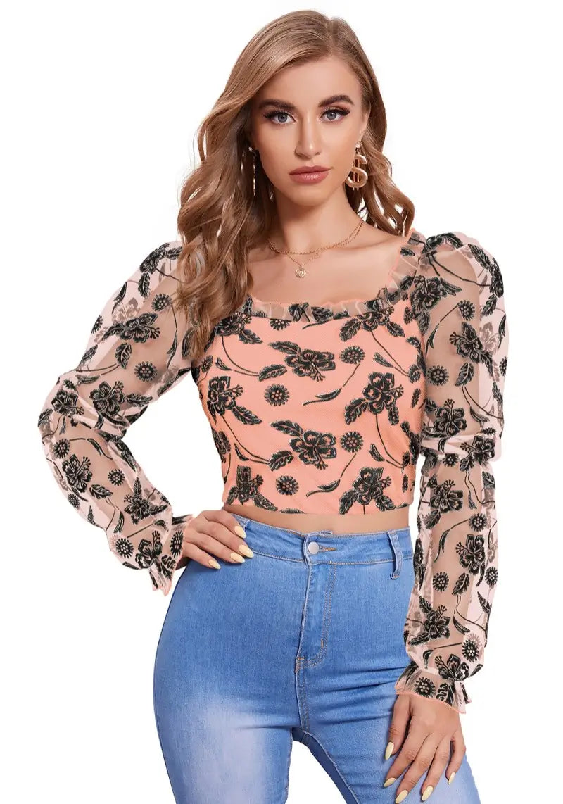 Model wearing peach crop top with sheer puff sleeves and floral print – front view