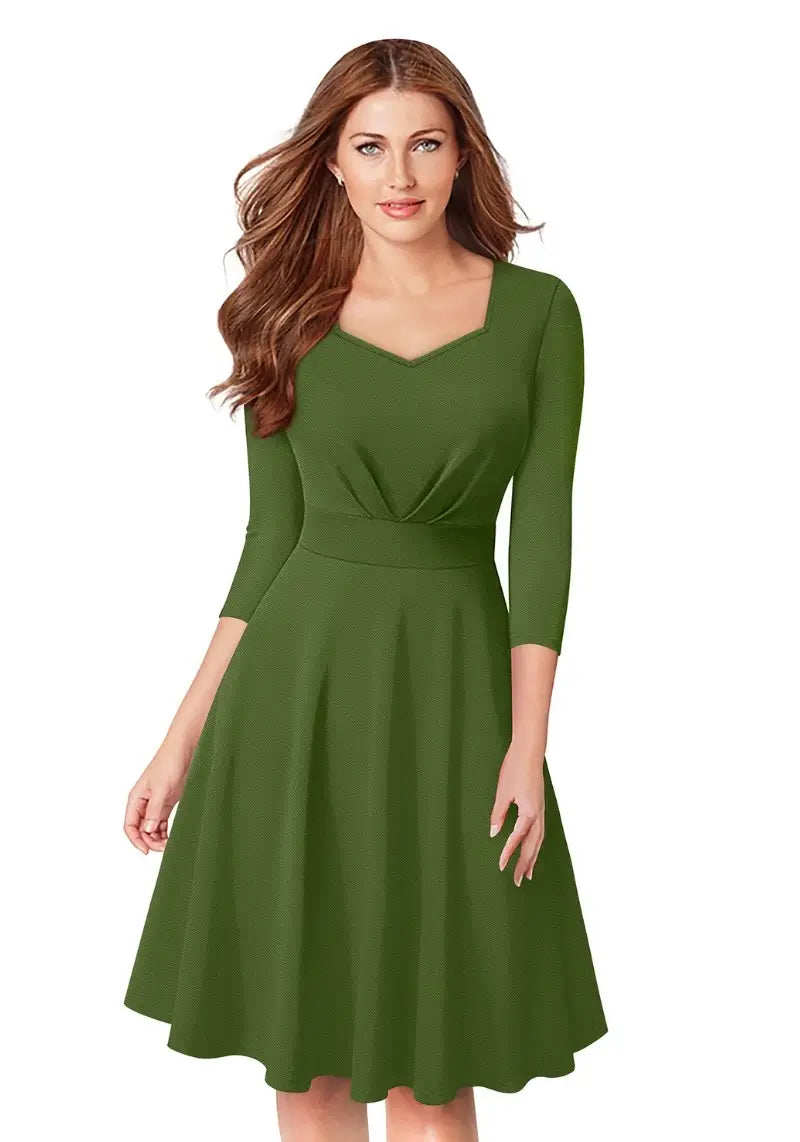 Model wearing Henna Green Fit & Flare Flounce Hem Dress with diamond neckline and 3/4 sleeves, posing front-facing.