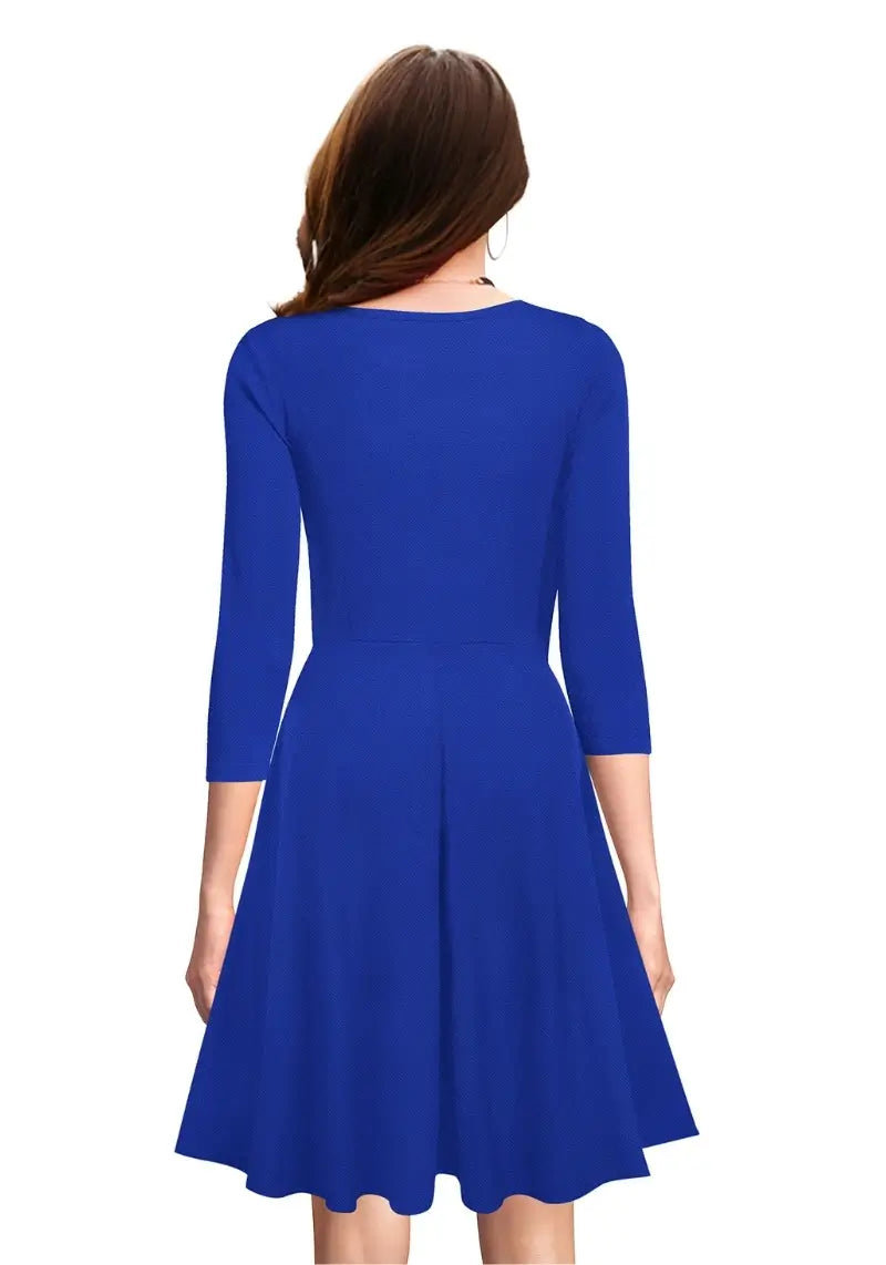 Back view of the model wearing Royal Blue Fit & Flare Flounce Hem Dress with diamond neckline and 3/4 sleeves, posing front-facing.