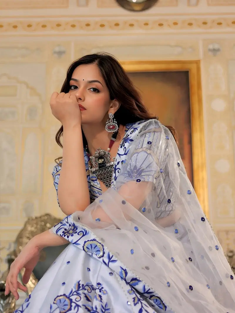 Sitting pose of model wearing White and Blue Heritage Lehenga Choli with dupatta Set.