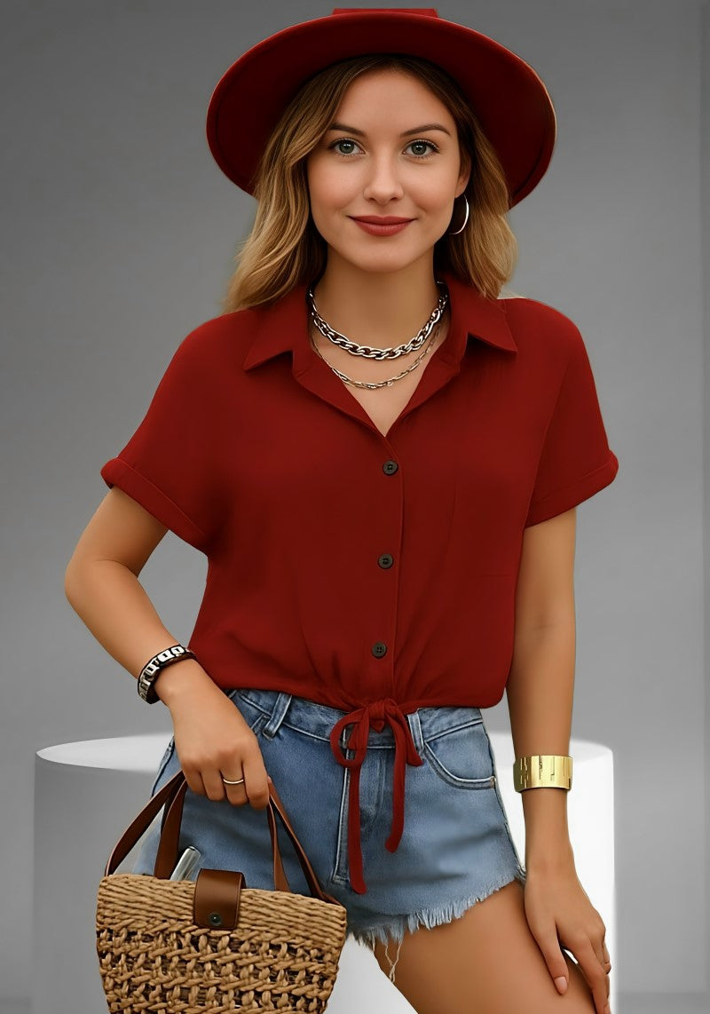 Model wearing Snazzyhunt burgundy short-sleeve button-up shirt in premium viscose with tie-front detail, paired with light blue high-waist frayed denim shorts and woven straw tote — Snazzyhunt chic casual summer look.