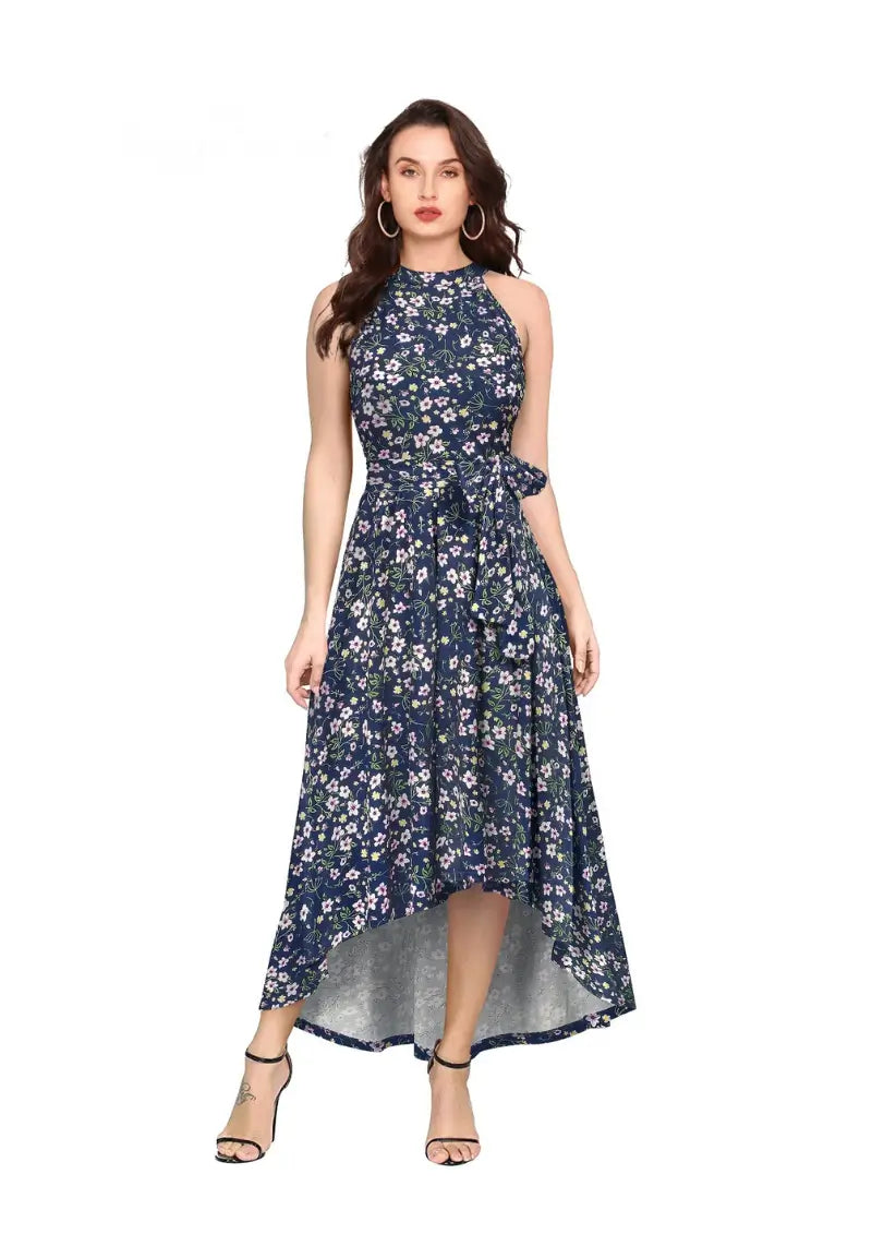 A woman wearing a blue floral printed halter neck one-piece dress with a high-low knee design, paired with ankle strap sandals.