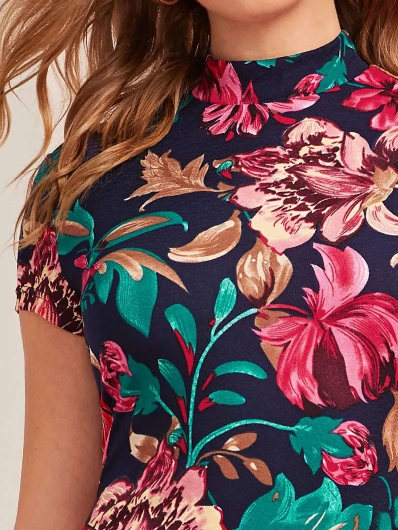 Close up of model wearing Midnight Bloom Floral Bodycon Dress featuring bold floral print, mock neckline, short sleeves, and a curve-hugging silhouette.
