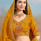 Close-up of floral zari and resham embroidery with sequins on mustard yellow georgette lehenga choli, model showing  the choli embellishment