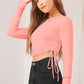 Side profile of model in peach long sleeve crop top with ruched drawstring detail
