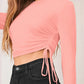 Close-up of peach ruched drawstring design and fabric detail on long sleeve crop top